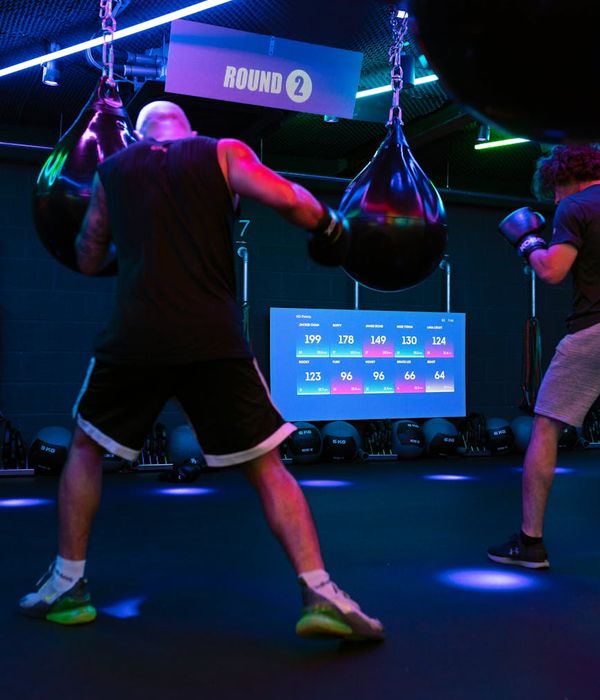 Man performing a strength exercise in a modern gym with dark background.